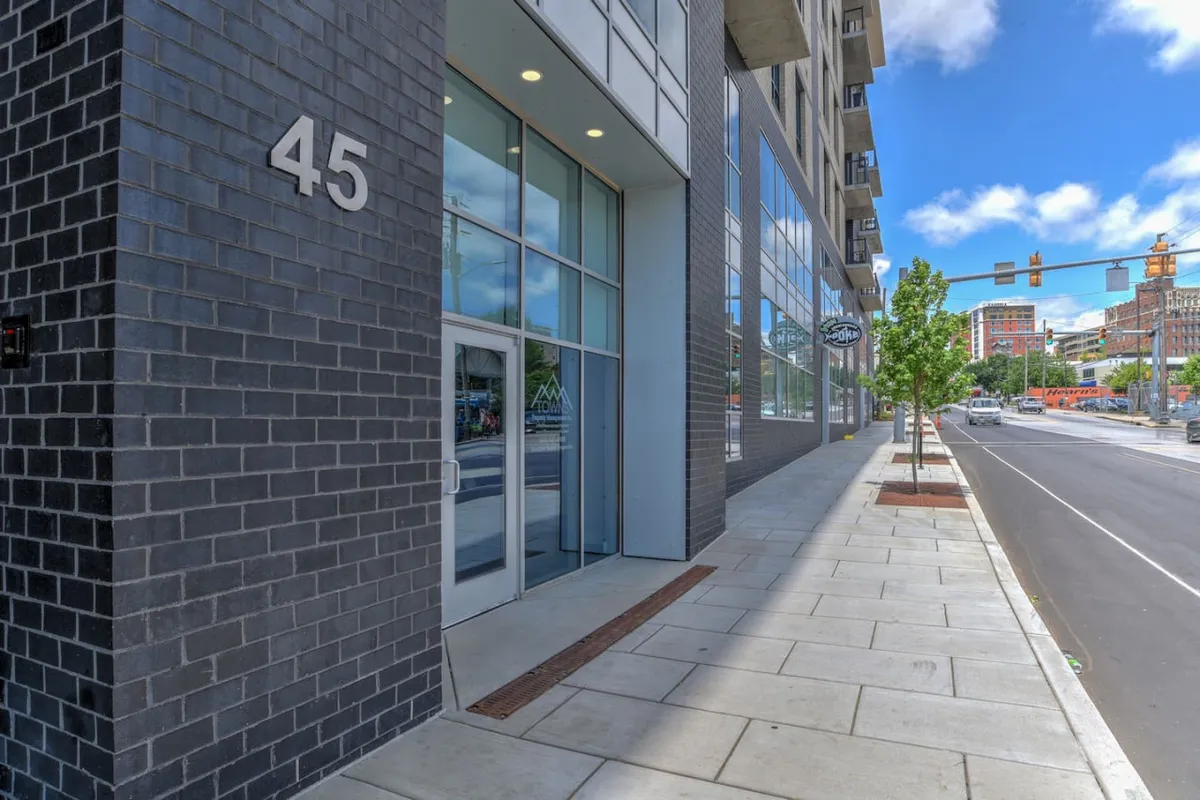 The image displays the building's exterior facade, marked with a prominent number '45', large glass windows, and a bustling sidewalk. It conveys a sense of modern urban living and highlights the building's secure, professional presence within the city environment.