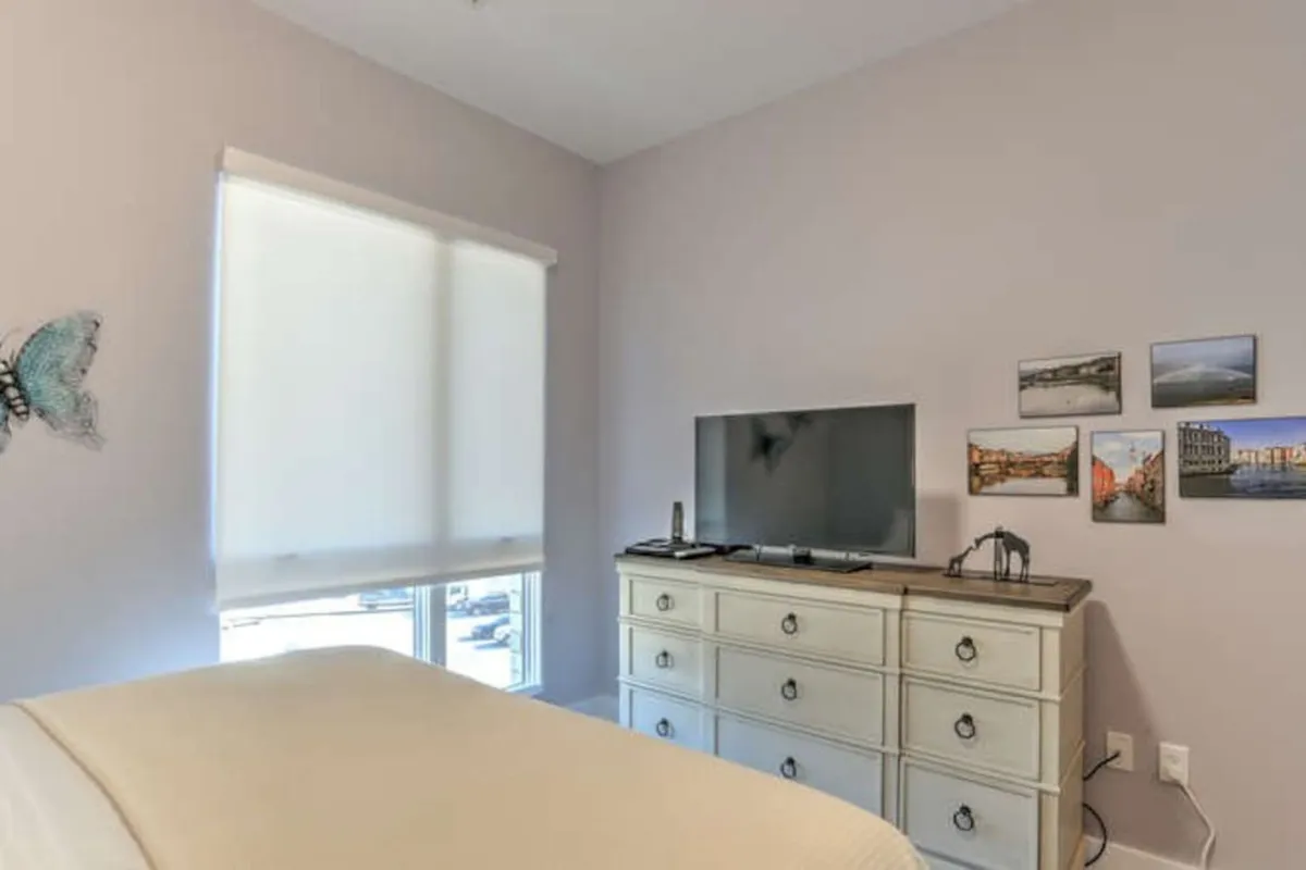 This image captures a tranquil interior scene featuring a dresser, television, and wall art with butterfly decor. The space radiates calm, suggesting a place where one can relax, enjoy a morning coffee, or catch up on work emails in a peaceful setting.